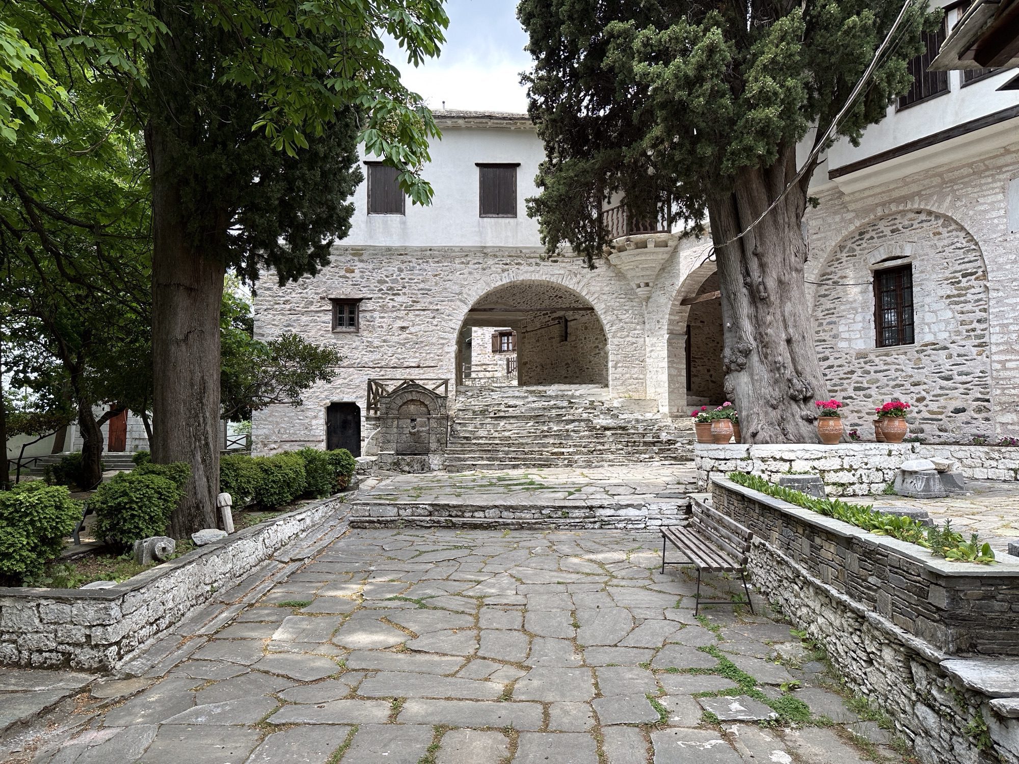 Grijze stenen gebouwen rond binnenplein met bomen in Makrinitsa, Pelion