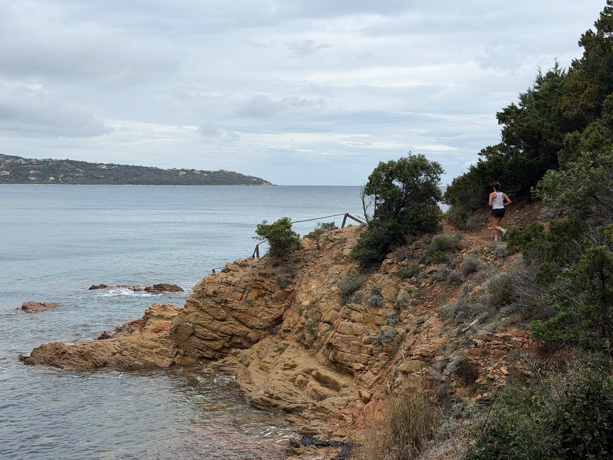 Jogster op rotsweg langs baai.