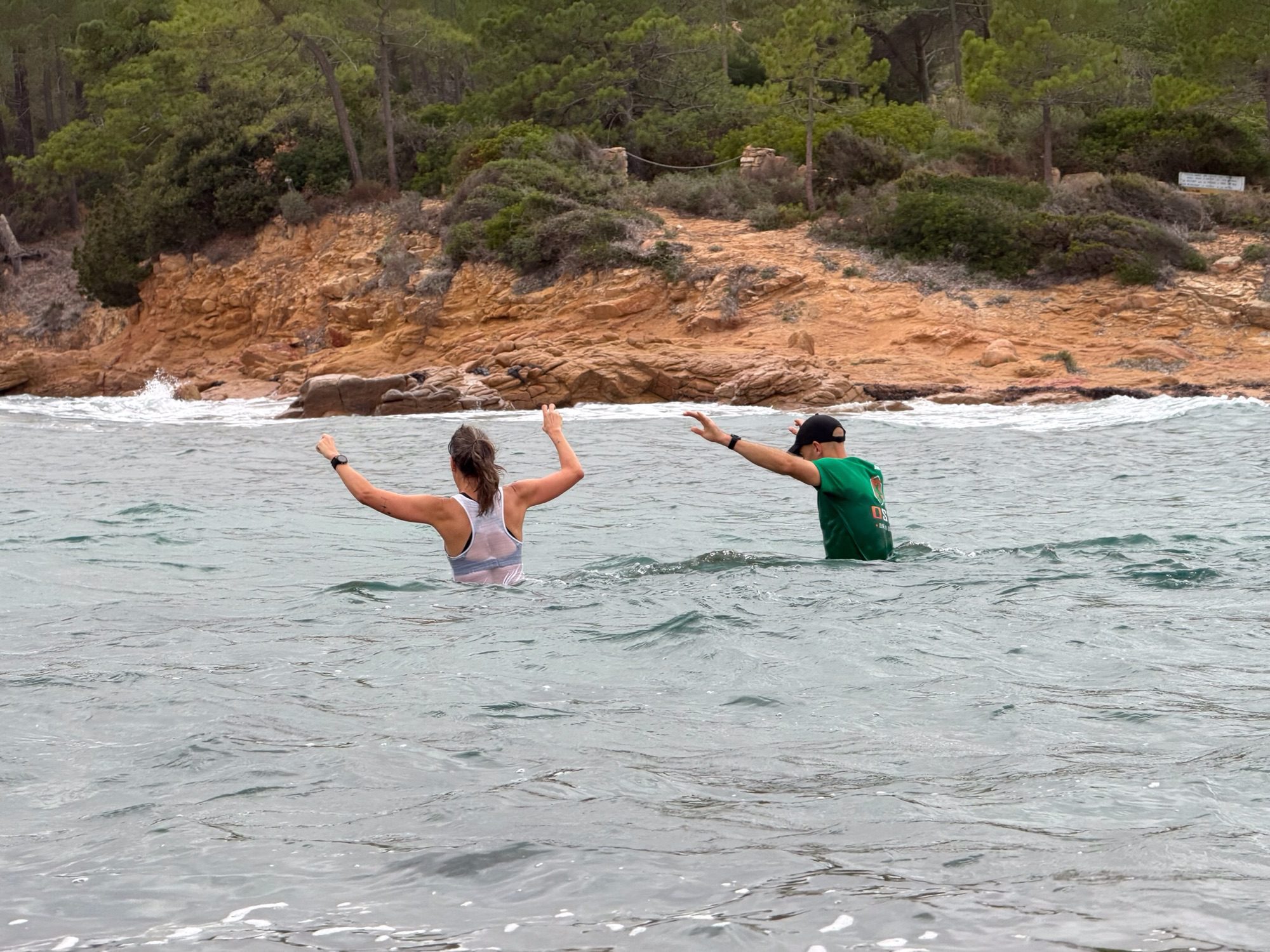 Joggers tot aan het middel in de zee tussen Pinarello en het eiland.