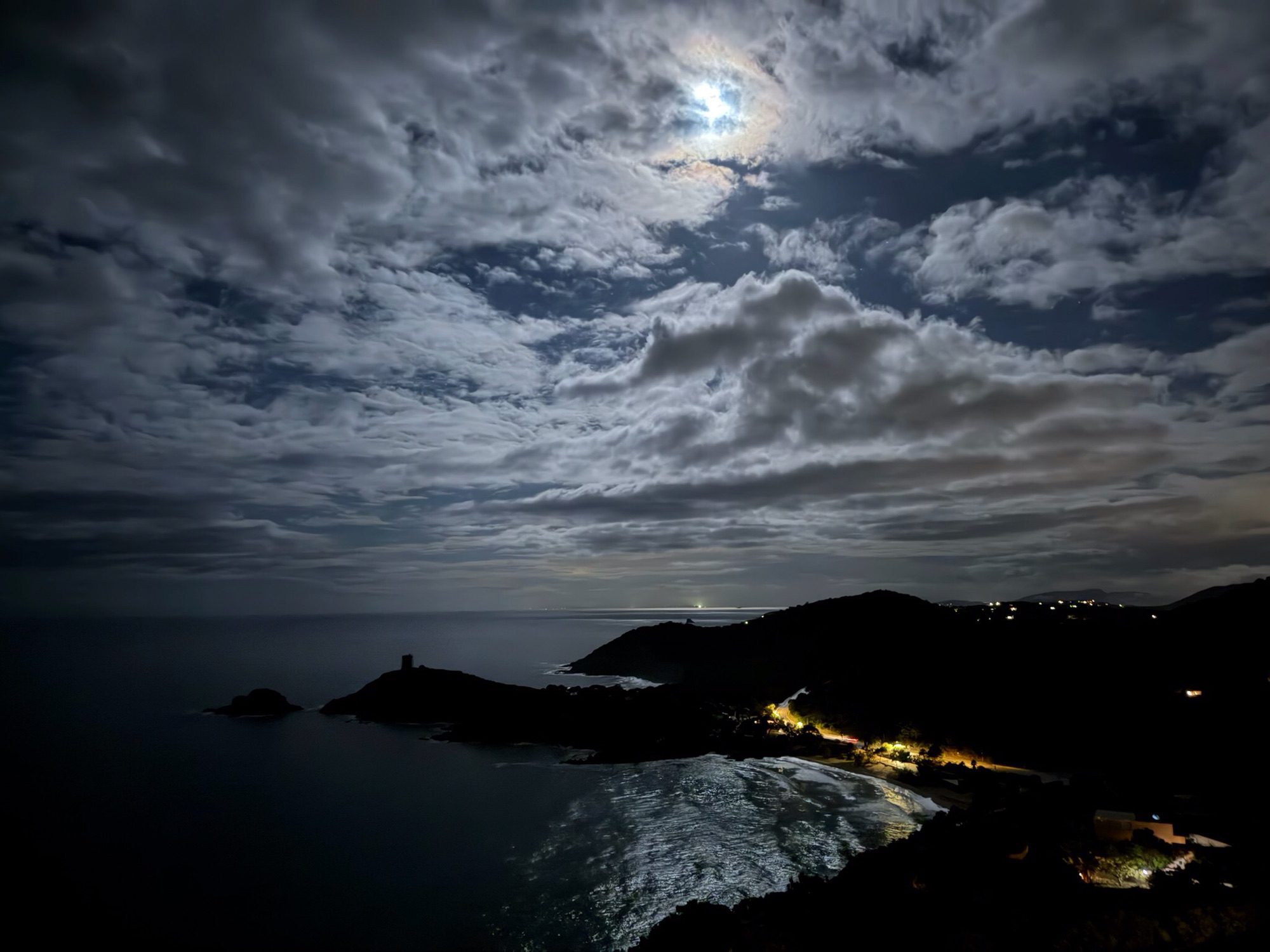 Maan, donkere avondhemel, weerspiegeling in de baai.