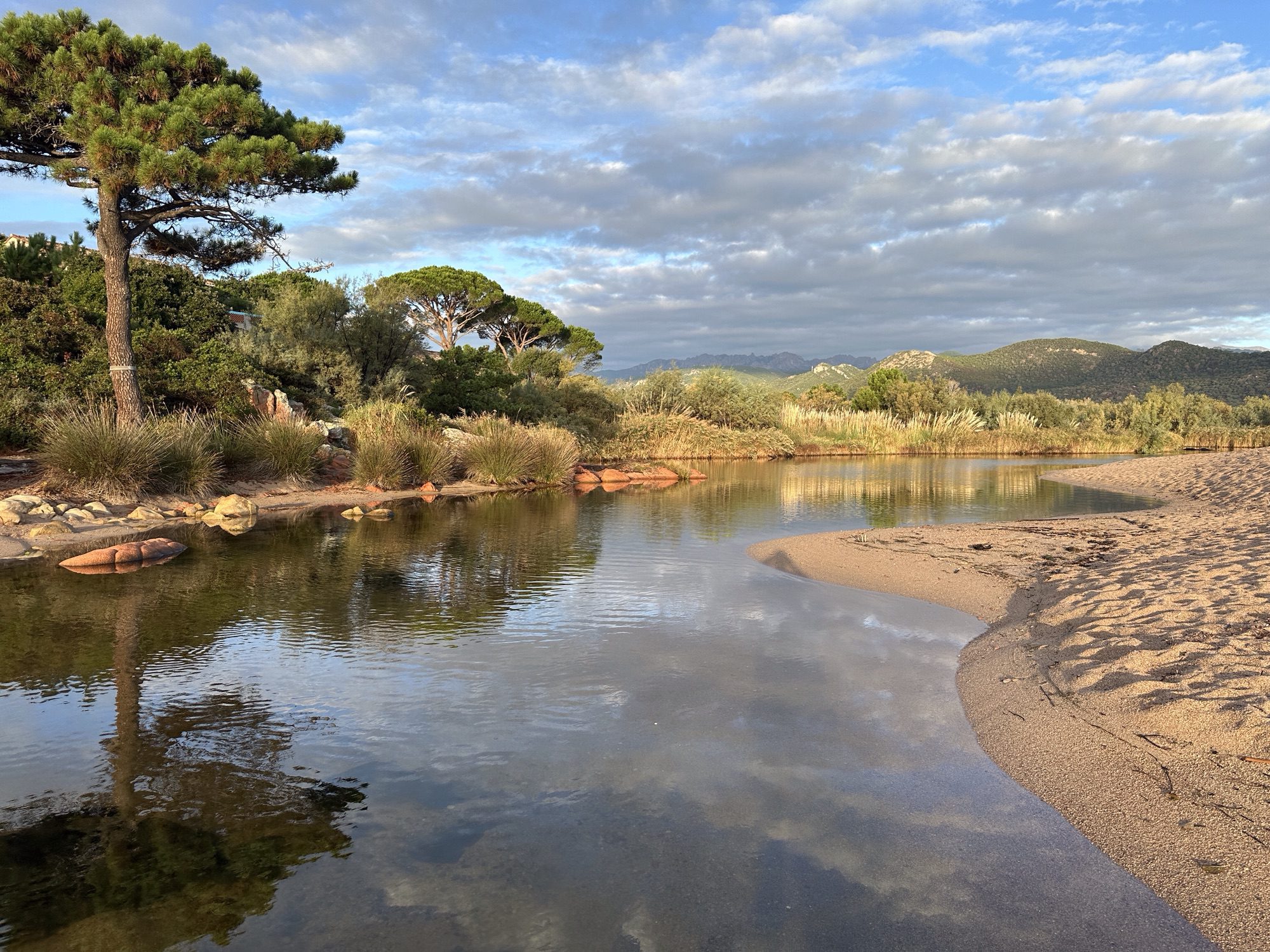 Meertje en rivier achter zandstrand.