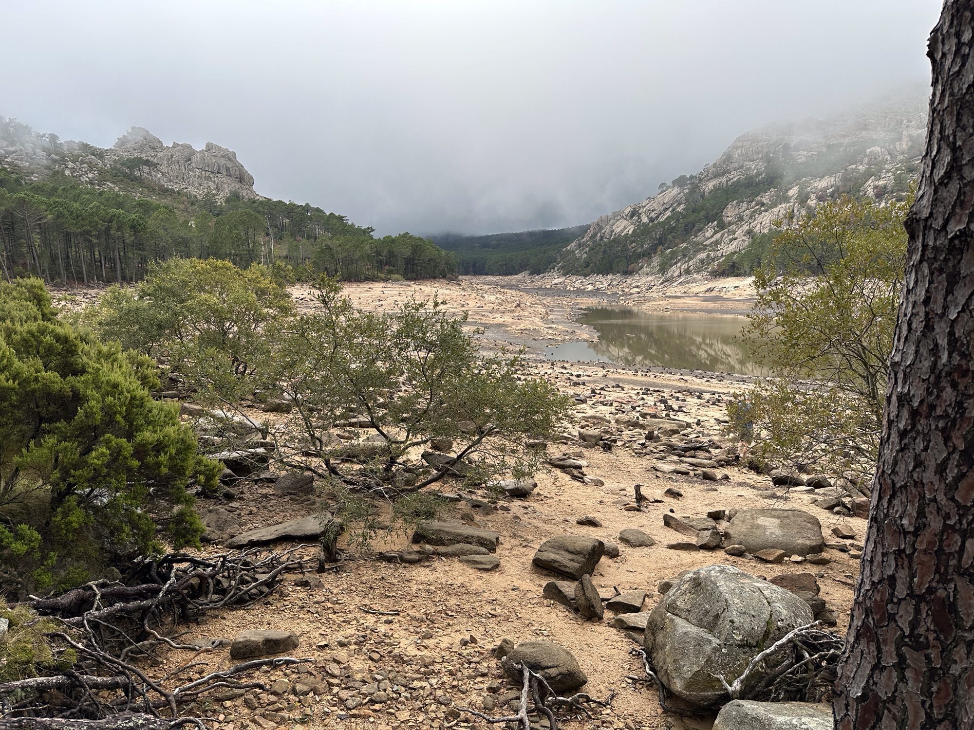 Panorama met bergen, lage wolken, leeg stuwmeer.