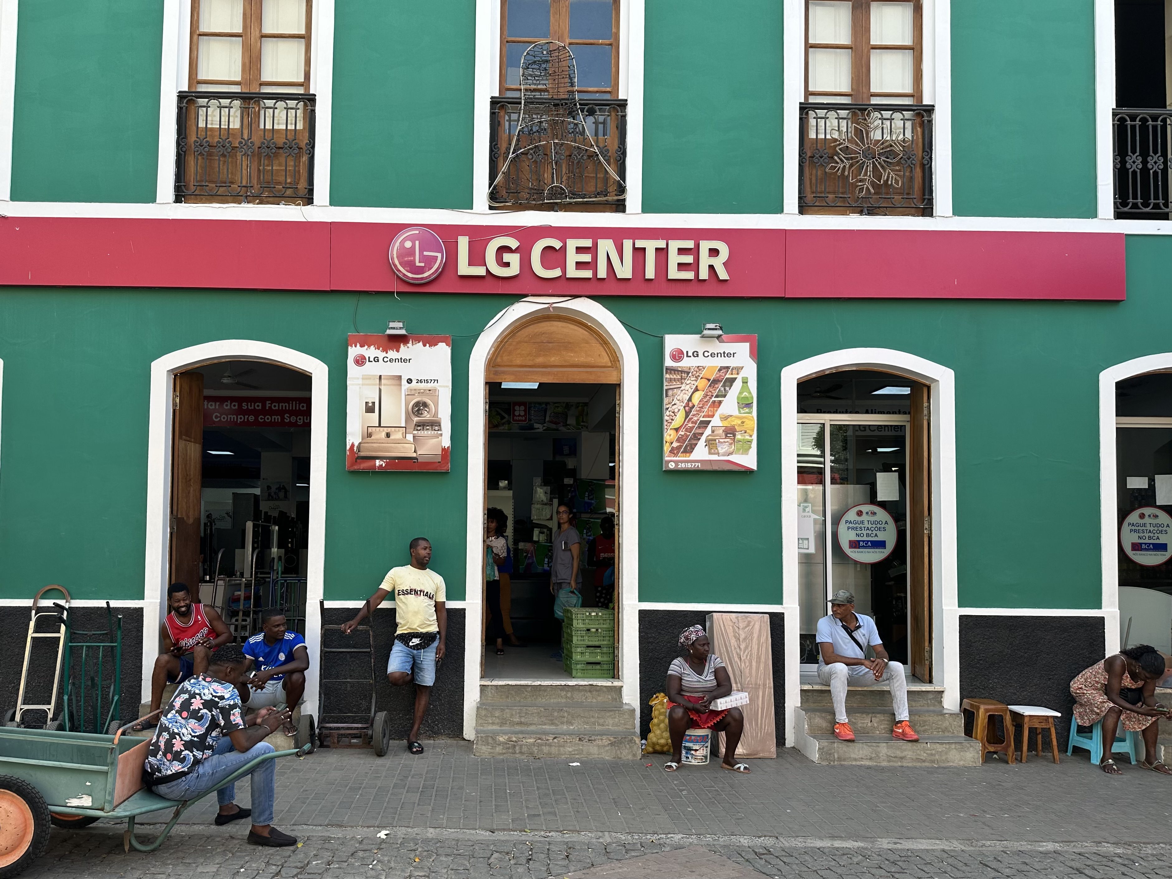 Groene gevel met op drempels zittende mensen in Praia.