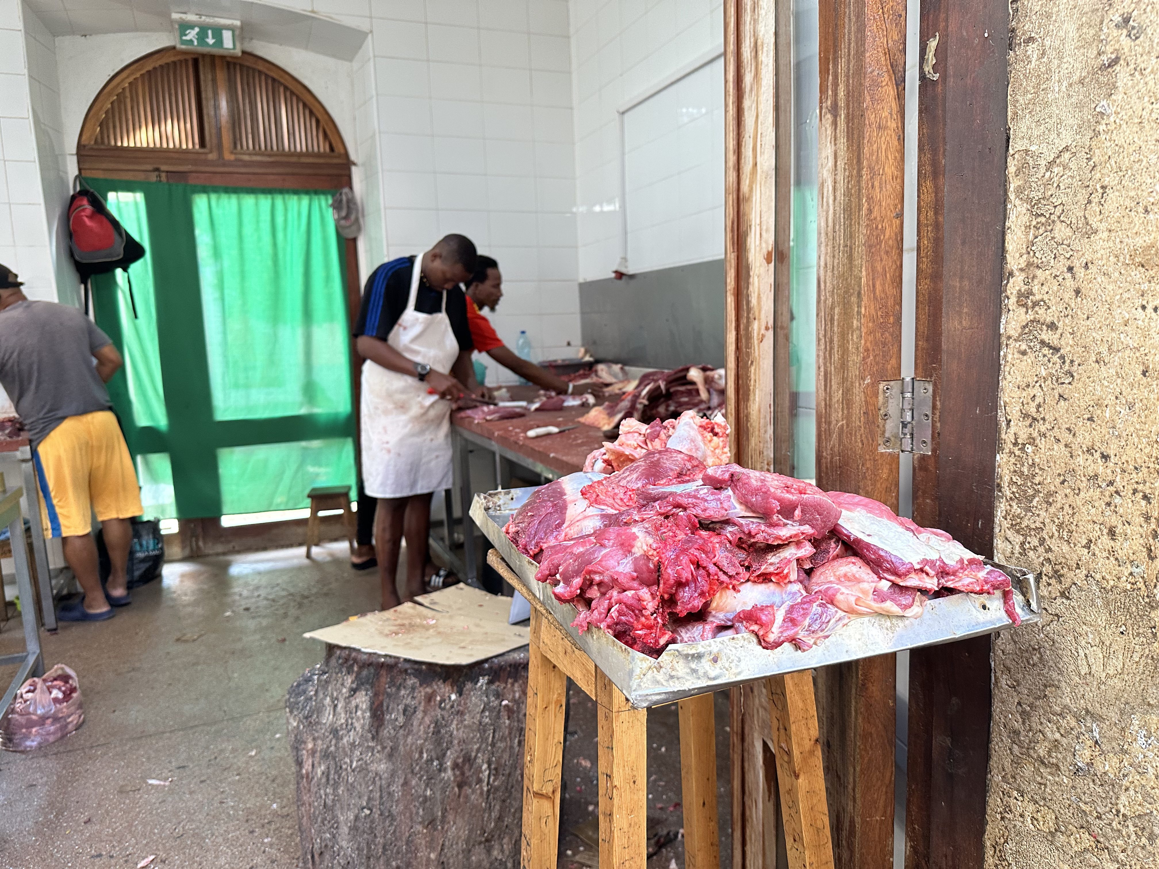 Slager aan het werk in Praia: grote lappen vlees op tafel.